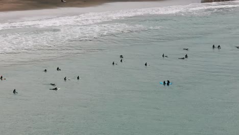 Drone-aerial-shot-of-surfers-in-wet-suits-waiting-for-waves-to-surf
