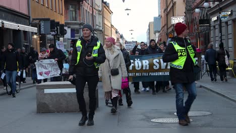 Covid-law-protesters-in-Sweden-march-toward-camera-with-banner