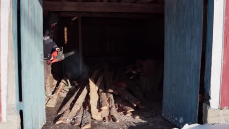 Man-Sawing-Wood-Using-Electrical-Chainsaw---Wide-Shot