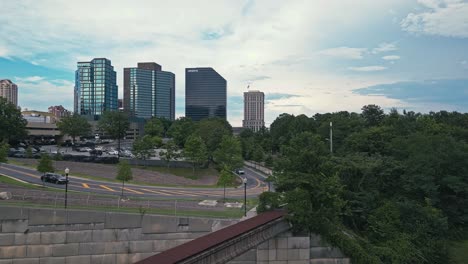 Rising-drone-shot-of-traffic-on-highway-and-modern-tower-buildings-in-background