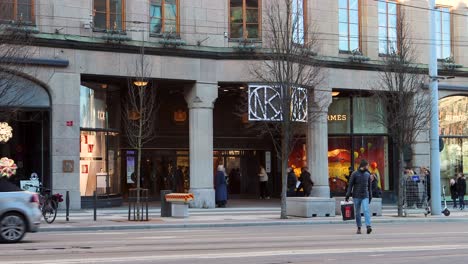 Street-traffic-by-department-store-NK-in-Stockholm,-man-crosses-street