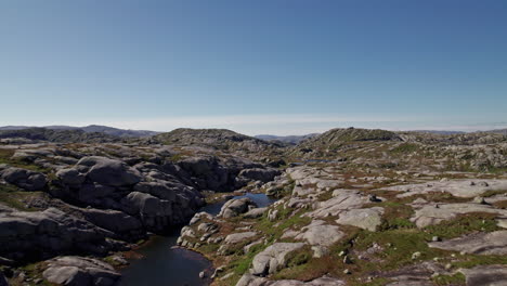 Aerial-dolly-shot,-pushing-in-over-the-mossy,-rocky-landscape-in-the-Rogaland-region-of-Norway