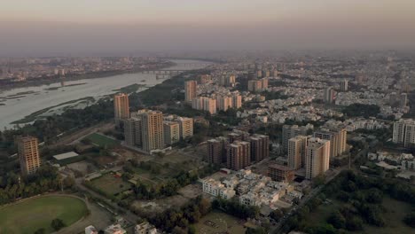 Aerial-Drone-View-Camera-Going-Forward-Where-A-Large-Cricket-Ground-And-Surrounding-High-Rise-Buildings-And-Low-Rise-Buildings-Are-Seen