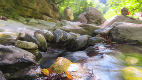 Bach-Fließt-Durch-Felsigen-Bach-In-üppigem-Wald,-Sonnenlicht-Schimmert,-Zeitraffer