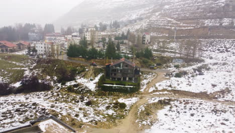 Drone-footage-of-chalet-in-Kfardebian,-with-streets-covered-in-snow-and-fog