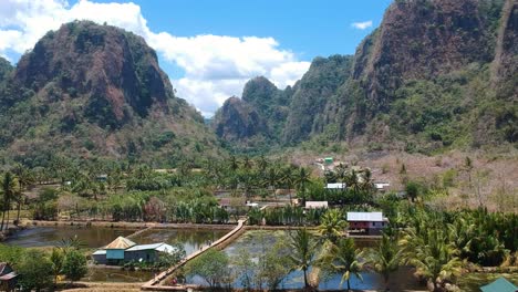 Aerial-drone-of-beautiful-hidden-gem-Rammang-Rammang-Village-with-giant-limestone-cliffs-and-huge-karst-mountains-in-Sulawesi,-Indonesia