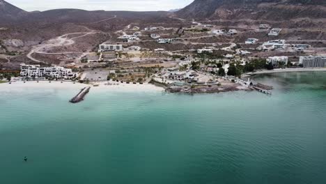Aerial-shot-of-Playa-Caimancito-and-La-Concha-in-La-Paz,-Baja-California,-showcasing-the-tranquil-turquoise-waters-and-coastal-resorts