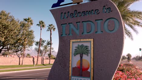 Welcome-to-Indio,-California,-City-of-Festivals-sign-close-up-and-tilt-down-with-vehicles-driving-by