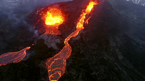 An-aerial-cinematic-sequence-captures-the-distinct-imagery-of-two-erupting-volcanoes,-showcasing-stunning-perspectives-filmed-with-a-4K-drone-as-lava-cascades-down-below