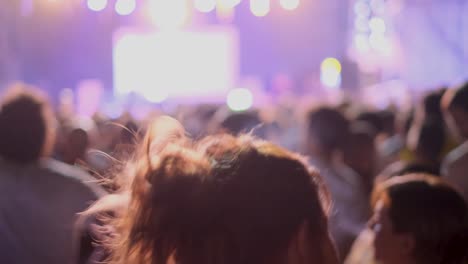 Slow-Motion-Rear-Silhouette-Shot-of-Young-Caucasian-Woman-Dancing-at-Concert-with-Bright-Orange---Purple-Lights