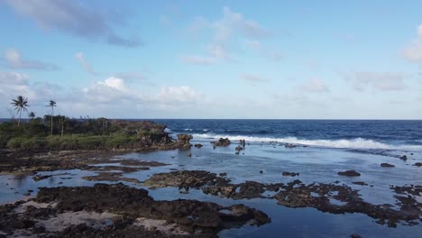 Flying-over-island-rocks,-waves-crashing-into-shore