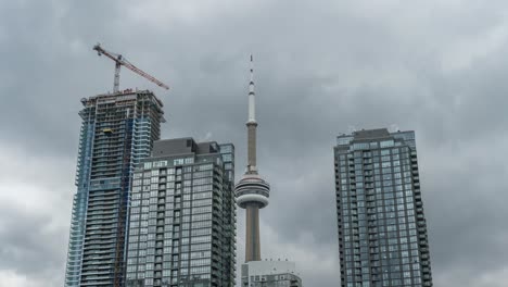 Crane-On-Top-Of-Condominium-Under-Construction-With-CN-Tower-In-The-Background-In-Toronto,-Canda