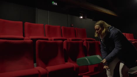 Toma-Manual-De-Una-Mujer-Colocando-Un-Asiento-Para-Niños-En-Una-Silla-De-Cine-Roja.