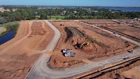 Yarrawonga,-Victoria,-Australia---8-March-2024:-Aerial-overview-of-two-tip-trucks-and-an-excavator-working-at-a-dirt-stockpile-at-Silverwoods-Estate-in-Yarrawonga