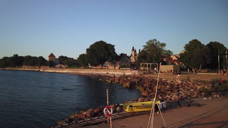 Static-slomo-of-people-walking-by-water-at-sunset-in-Visby,-Gotland