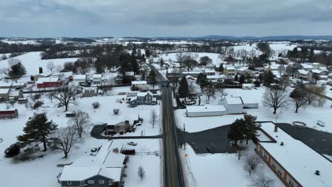 Landing-drone-shot-showing-main-street-of-suburban-neighborhood-in-Winter-Snow