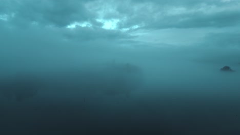 Drone-approaching-the-islands-in-the-middle-of-the-Windermere-Lake,-in-the-town-of-Bowness-on-Windermere-in-Westmorland,-Cumbria,-in-England