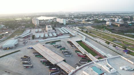 Aerial-Shot-of-Sunrise-near-The-Bus-Station-with-Buses-Passing-Through