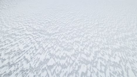 Windswept-snow-pattern-spreads-jagged-sharp-peaks-across-ice-white-lake-in-Suwalki-Gap-Masuria-Poland