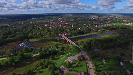 Panoramic-aerial-view-of-Venta-river-waterfall-and-old-historic-bridge