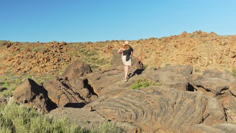 Mother-carries-baby-in-ergo-carrier-while-climbing-rocks-in-Teide-national-park,-Tenerife