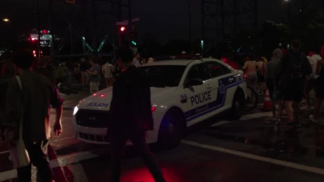 Montreal-police-car-with-flashing-lights-at-night-with-a-crowd-of-people-around-at-slow-motion,-spvm,-montreal,-quebec,-canada