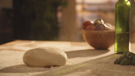 Medium-close-up-of-dough-piece-being-thrown-onto-table,-flour-dust-spreading-in-the-air