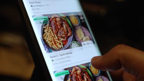 Browsing-the-Deliveroo-food-app-on-a-smartphone,-swiping-through-the-tantalizing-array-of-dining-options