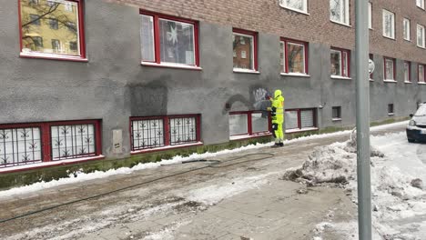 Worker-removes-graffiti-from-building's-exterior-wall-in-Stockholm
