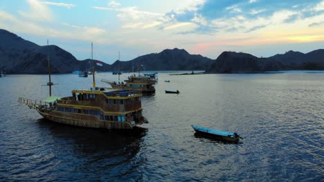 A-group-of-ships-anchored-off-the-coast-of-Padar-Island,-near-Komodo-in-Indonesia,-captured-from-a-drone-during-the-evening