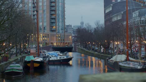 Filmische-Szenerie-Am-Abend-Mit-Blick-Auf-Die-Stadt-Den-Haag-Oder-Den-Haag-Mit-Lichtern,-Straßen,-Häusern,-Kanälen,-Wasser-Und-Schiffen-Im-Holländischen,-Europäischen,-Authentischen-Traditionellen-Architekturstil
