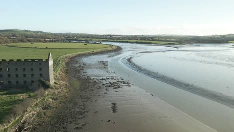 Las-Ruinas-De-La-Casa-Del-Molino-Utilizadas-Como-Almacenamiento-Agrícola-En-La-Orilla-Del-Río-En-El-Condado-De-Cork,-Irlanda