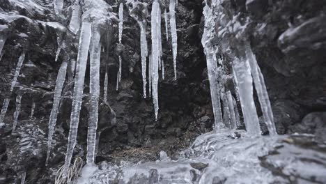 Icicles-hanging-from-rocky-surface-with-intricate-frost-patterns,-capturing-the-essence-of-winter