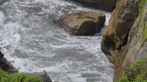 Wave-covers-a-boulder-off-of-cliff-coast-in-slow-motion---Punakaiki,-New-Zealand