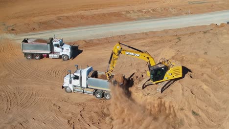 Yarrawonga,-Victoria,-Australia---8-March-2024:-Two-tip-trucks-working-with-an-excavator-to-move-dirt-around-building-site-at-Silverwoods-Estate-in-Yarrawonga