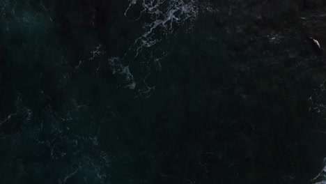 aerial-birds-eye-view-shot-of-large-and-powerful-waves-crashing-down-on-the-translucent-sea-by-the-rocky-coastline-by-hawaii