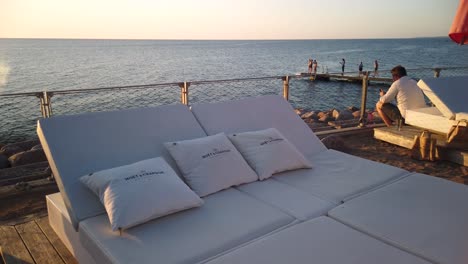 Moet-et-Chandon-pillows-on-sunbeds-at-seaside-resort-by-sunset,-Sweden