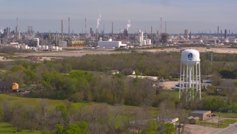 Drone-view-of-Baytown,-Texas-water-tower-and-refinery-in-the-background