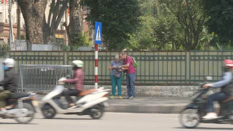 Touristen-Konsultieren-Eine-Karte-In-Hanoi,-Unschärfe-Eines-Vorbeifahrenden-Radfahrers