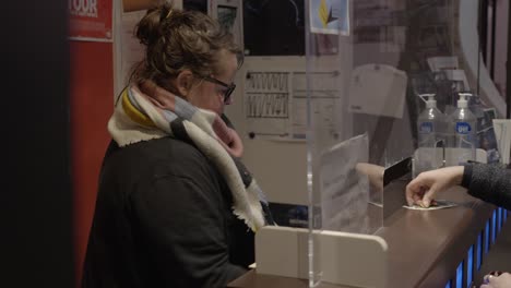 Attendant-handing-out-ticket-at-cinema-booth