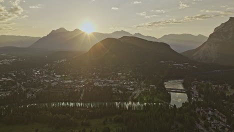 Banff-AB-Canada-Aerial-v16-drone-flyover-capturing-panoramic-landscape-views-of-quaint-townscape,-forested-valley,-Bow-river-and-mountain-ranges-at-sunrise---Shot-with-Mavic-3-Pro-Cine---July-2023