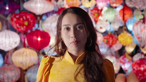 Woman-in-yellow-Ao-Dai-with-colorful-lanterns-in-Hoi-An-at-night,-traditional-Vietnamese-attire,-vibrant-atmosphere