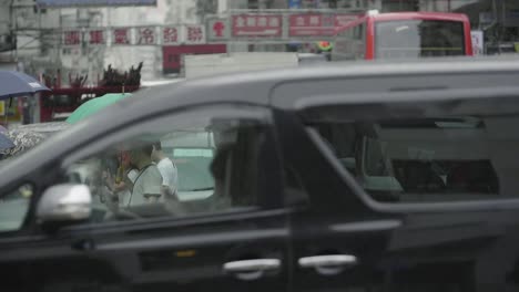 Hong-Kong-rush-hour-traffic-with-cars,-buses-and-pedestrians-crossing-an-intersection-on-an-overcast-day---slow-motion