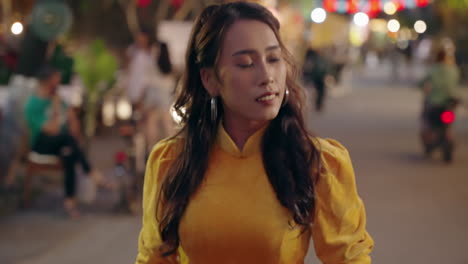 Close-up-slow-motion-shot-of-Vietnamese-woman-in-yellow-dress-walking-with-thinking-expression-at-night,-Hoi-An,-Vietnam