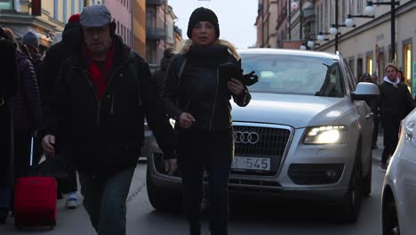 Frontale-Zeitlupe-Einer-Frau,-Die-Auf-Einer-Straße-In-Stockholm-Vor-Einem-Auto-Läuft