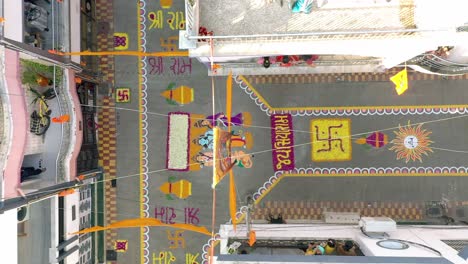 Vista-Aérea-De-Drones-Que-Va-Hacia-Donde-Se-Pintan-Grandes-Rangolis-En-La-Carretera-Y-La-Gente-Está-Pintando-Rangoli-Para-El-Edificio-Residencial-Jai-Siyaram-Es-Visible