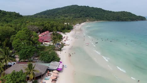 Drone-aerial-view-in-Vietnam-flying-over-Phu-Quoc-island-Sao-beach,-white-sand,-crystal-clear-blue-turquoise-water,-green-palm-trees-and-people-walking-on-a-sunny-day