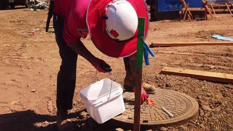 Gimbal-booming-up-shot-a-construction-worker-picking-up-loose-bolts-and-screws-at-a-modular-building-site-in-West-Los-Angeles,-California