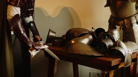 Tilt-down-of-tough-looking-knight-polishing-his-sword-in-a-medieval-armory