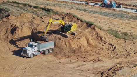 Yarrawonga,-Victoria,-Australia---8-March-2024:-Excavator-working-from-a-stockpile-of-dirt-filling-up-a-tip-truck-at-Silverwoods-Estate-in-Yarrawonga